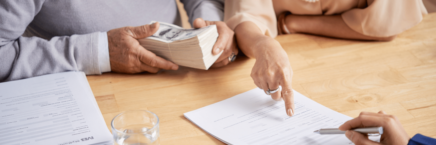 Couple signing documentation with lawyer and holding cash notes